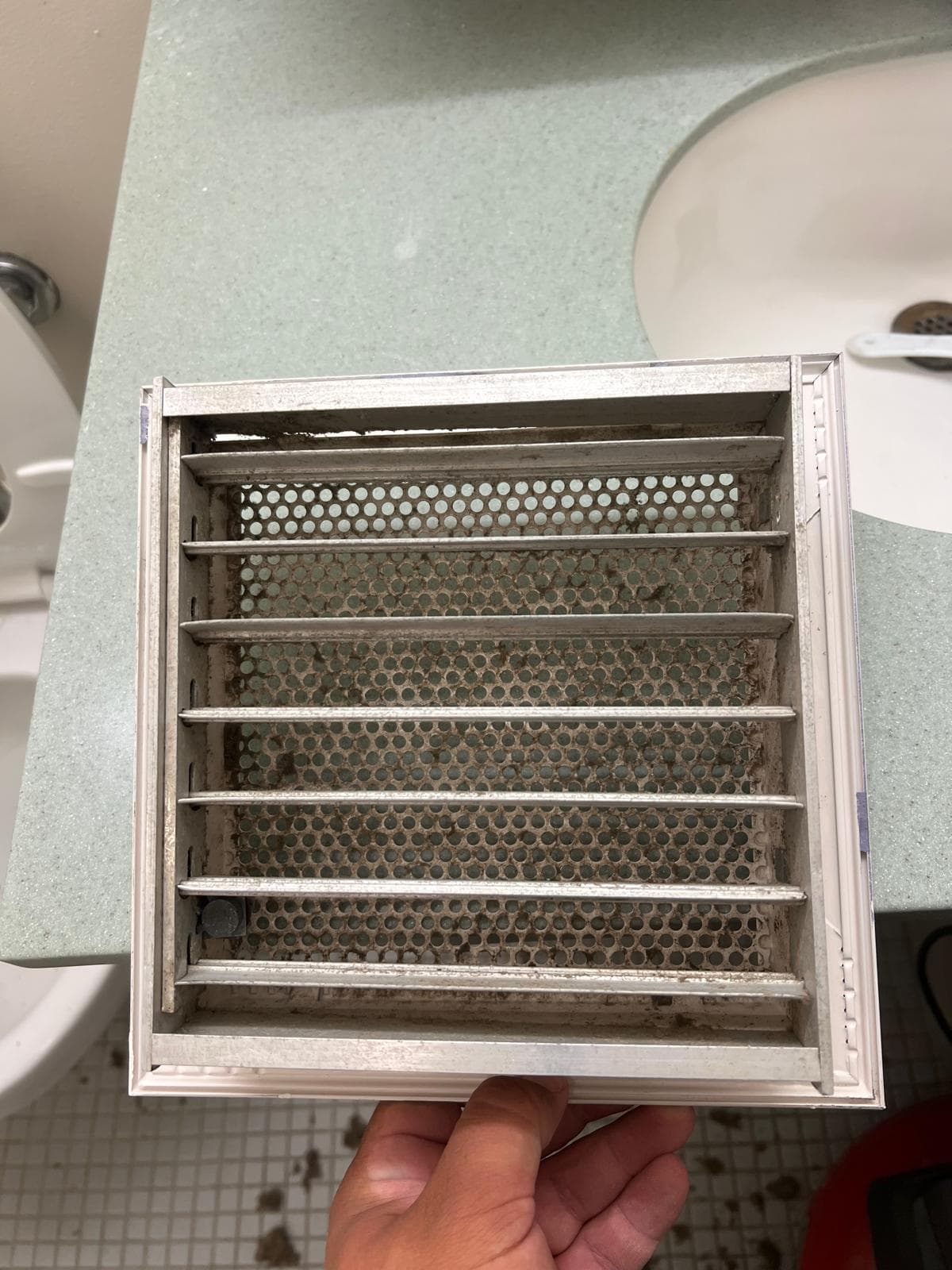 A return-air vent register caked with thick grey dust and lint before service, cleaned back to bare metal afterwards