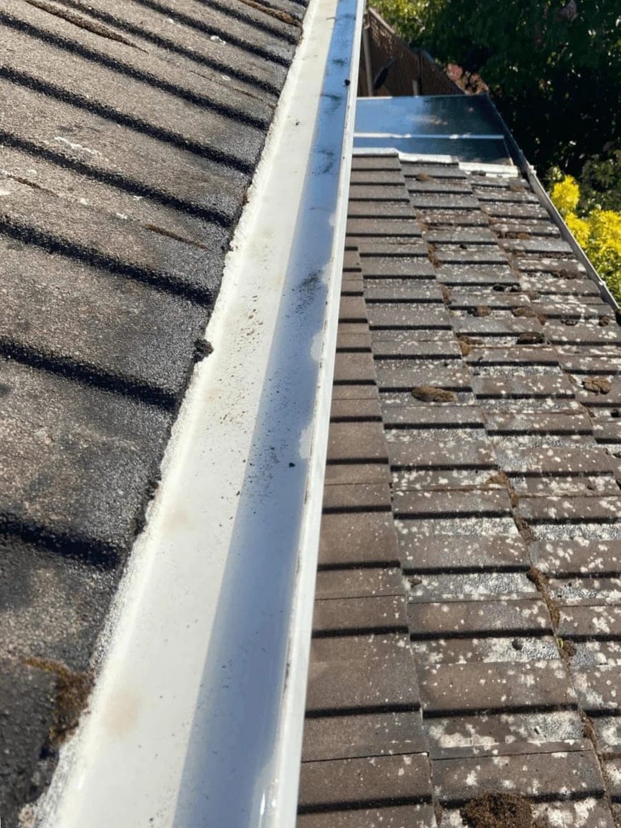 A roof gutter packed with moss and debris before clearing, and running clean afterwards